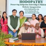 Rajeev Singh with traditional Adivasi elders and community representatives at the Hodopathy website inauguration in Giridih on 8 October 2026, with medicinal plants displayed at the venue.